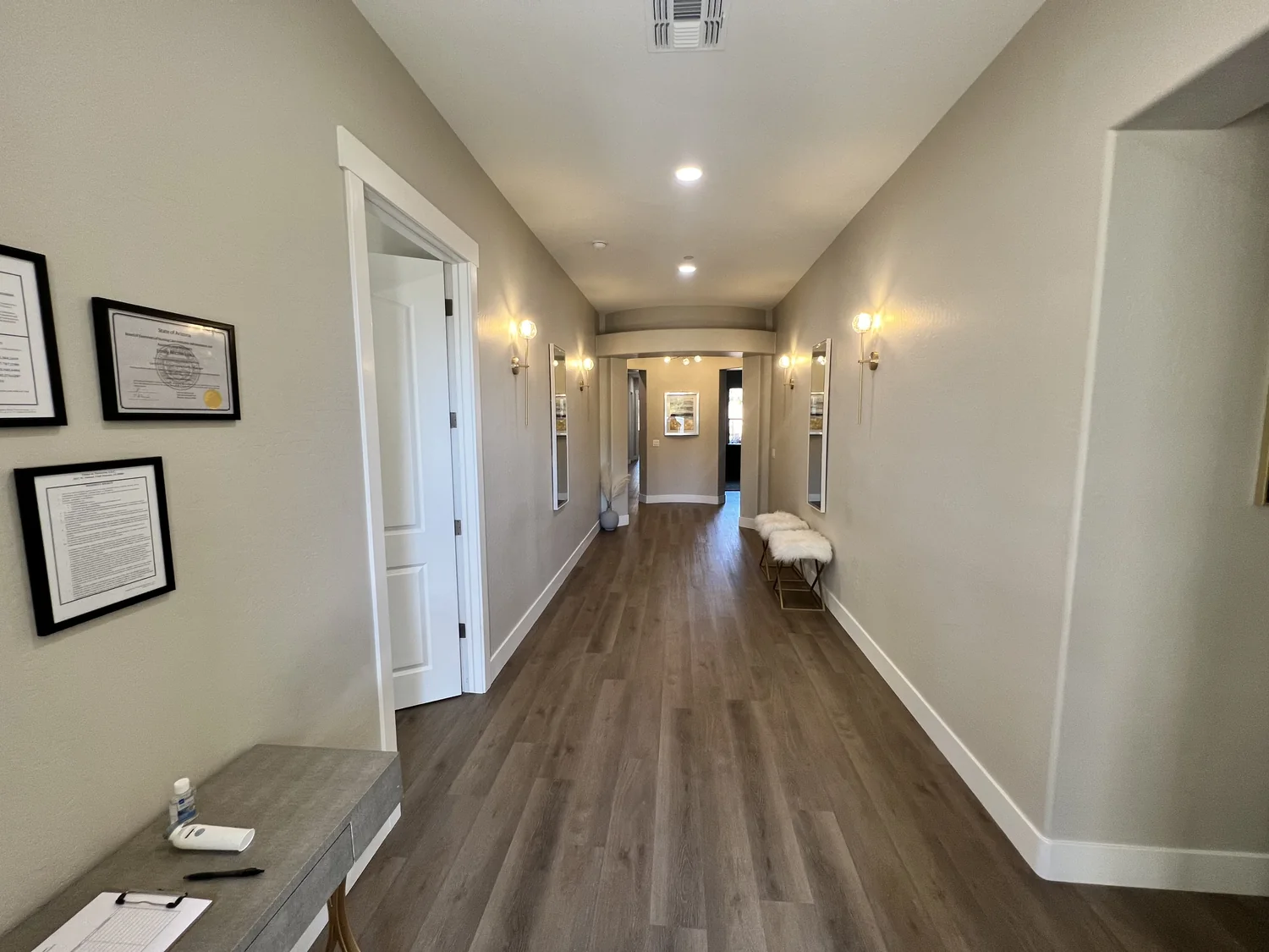 Warmly lit hallway with wood floors and wall sconces